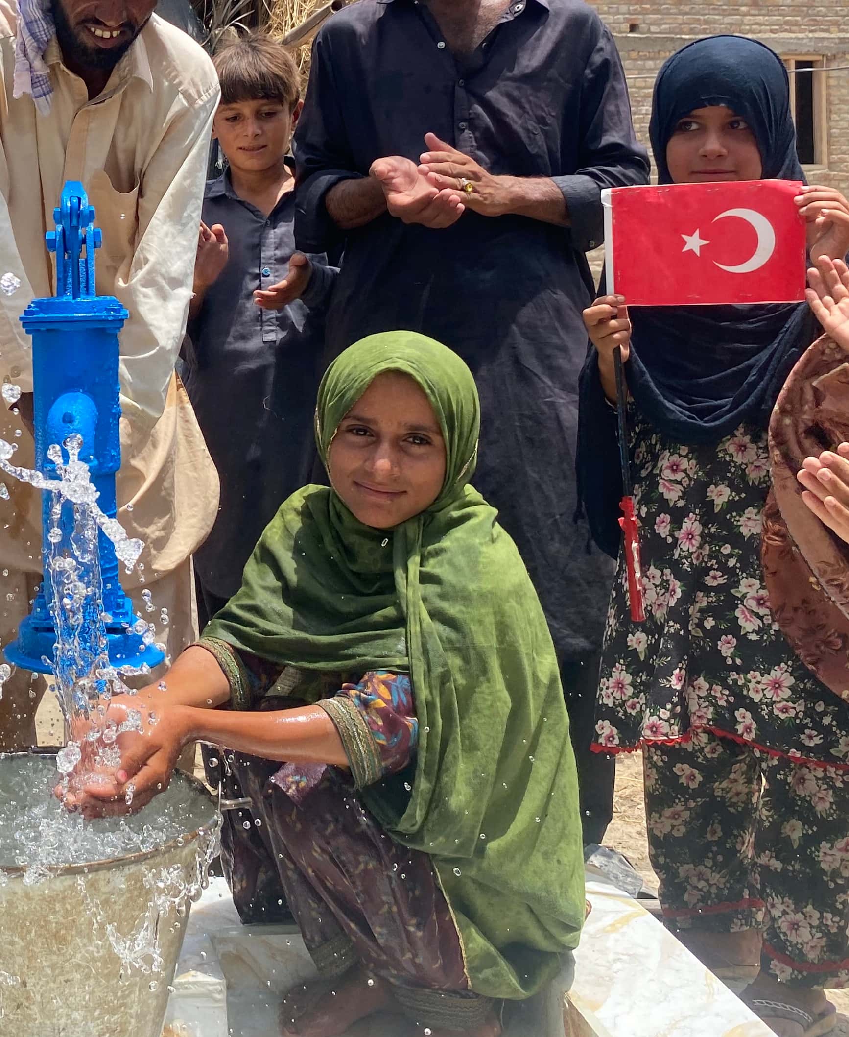 Pakistan'da yeni açılan kuyudan akan suyu gülümseyerek avuçlayan kız